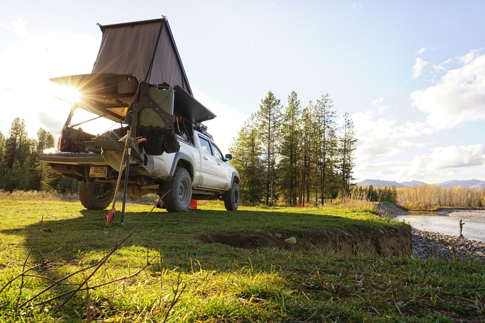 Rooftop tent on a truck with fisherman next to river