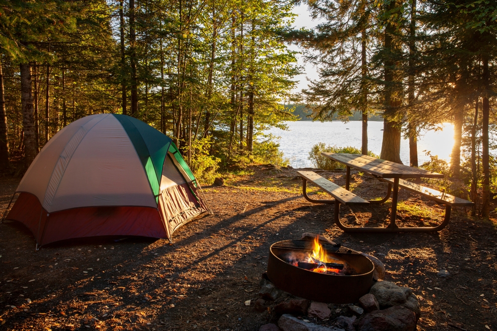 Tent Campsite on lake with campfire at sunset