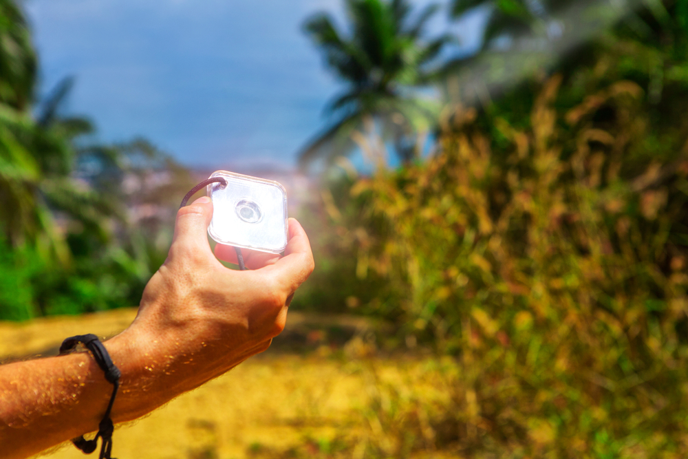 man's hand holds a signaling mirror