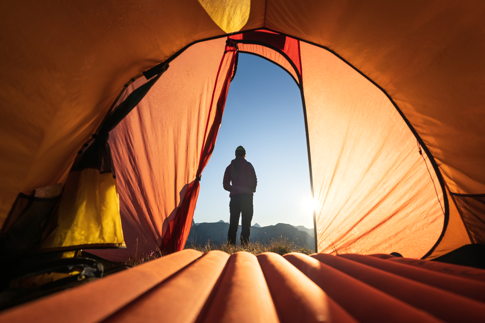 silhouette of a person standing outside their tent