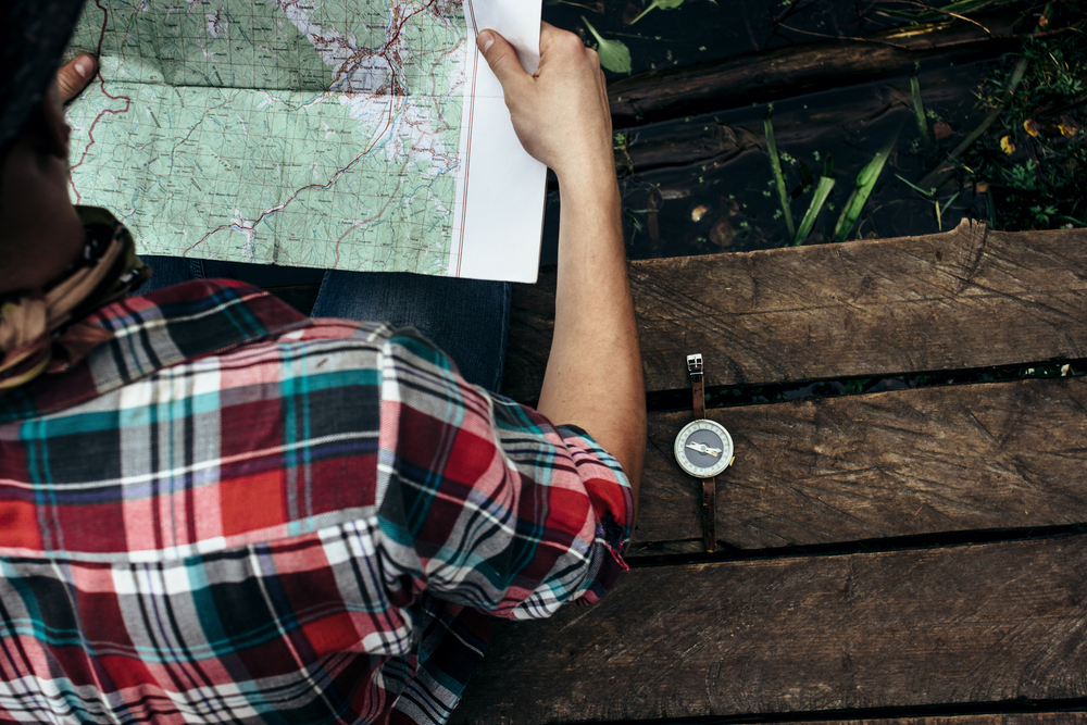 Man holding a map with a compass beside him