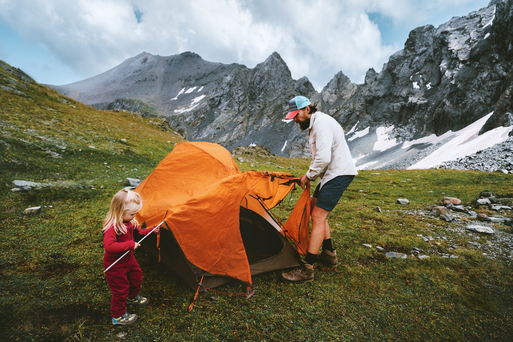  father and young daughter setting up a tent