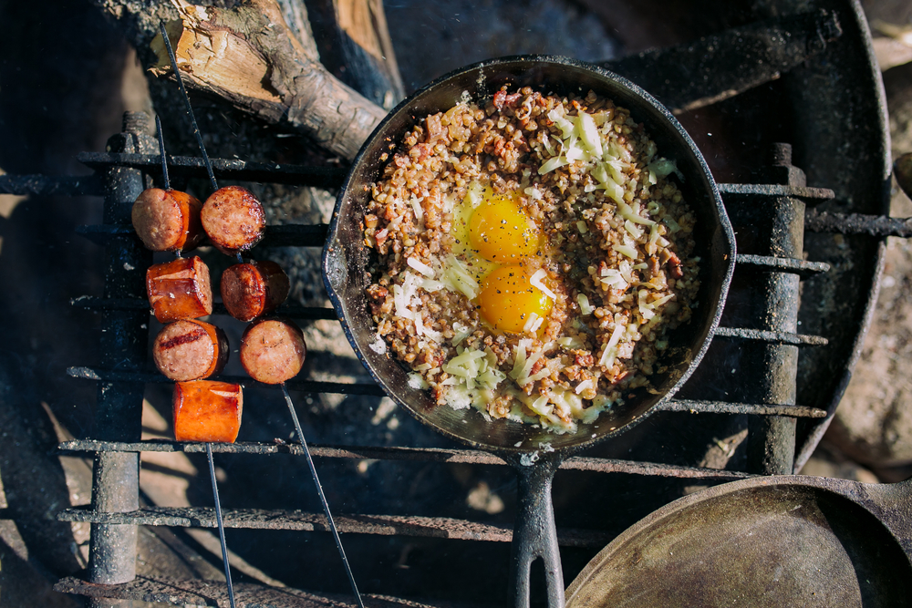 cooking eggs and sausage over a fire
