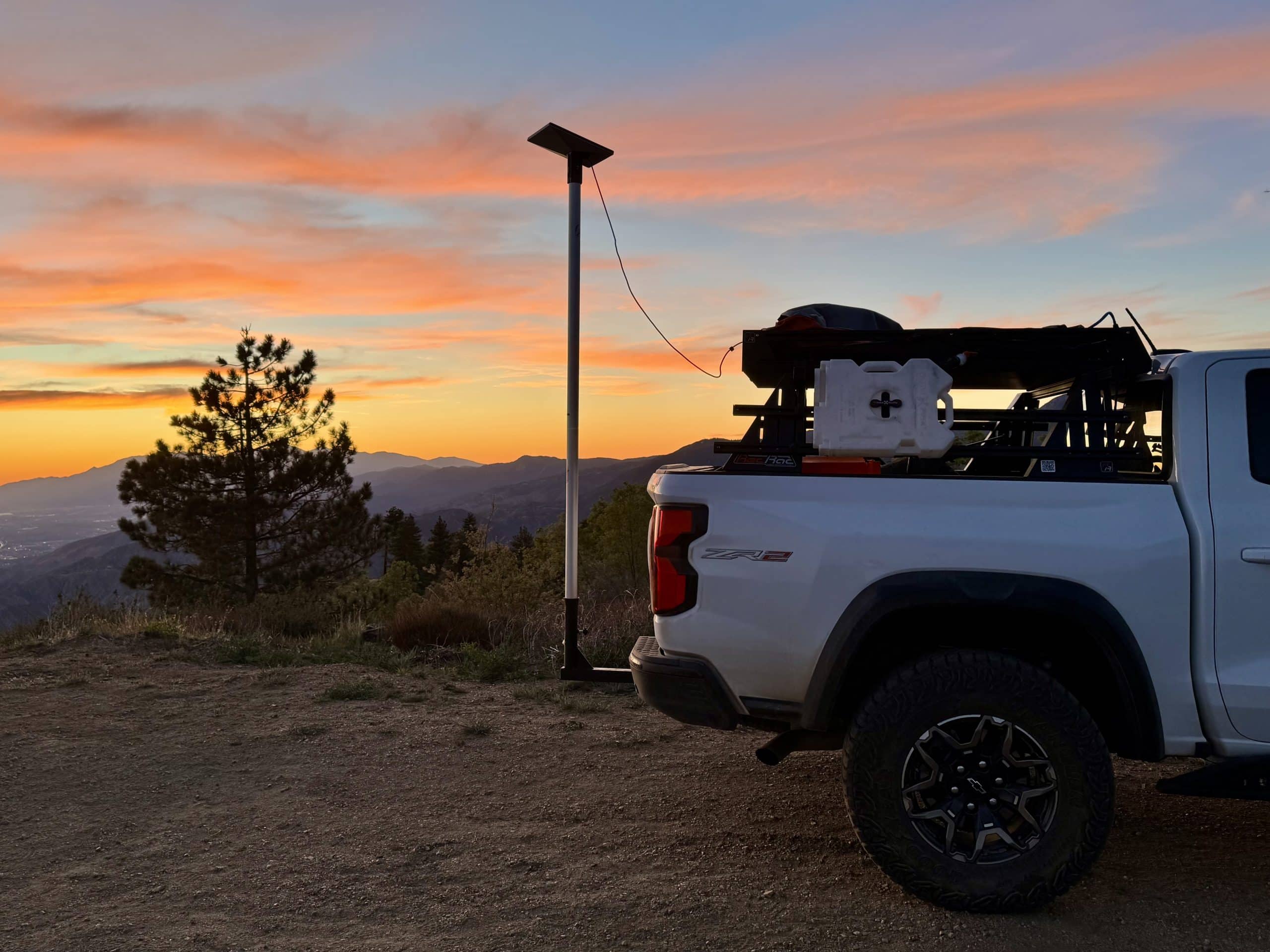 Starlink Mini on a Flagpole Buddy pole beside a white pickup truck at sunset on a mountain overlook