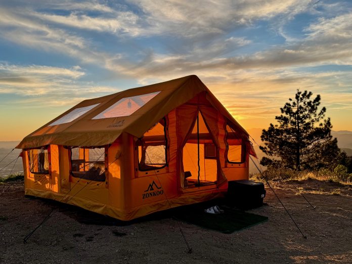 ZONKOO Vega inflatable hot tent with black frame poles set up in a forest clearing at dusk