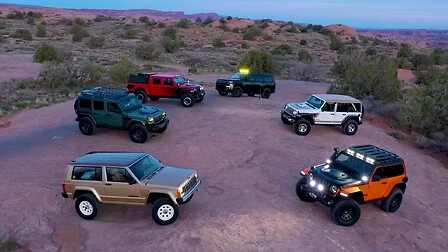 Lineup of six Jeep Easter Jeep Safari concept vehicles parked together on red rock terrain at dusk.