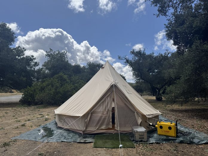 Stout 5M Pro bell tent standing dry under a partly cloudy sky the morning after a night of heavy rain.