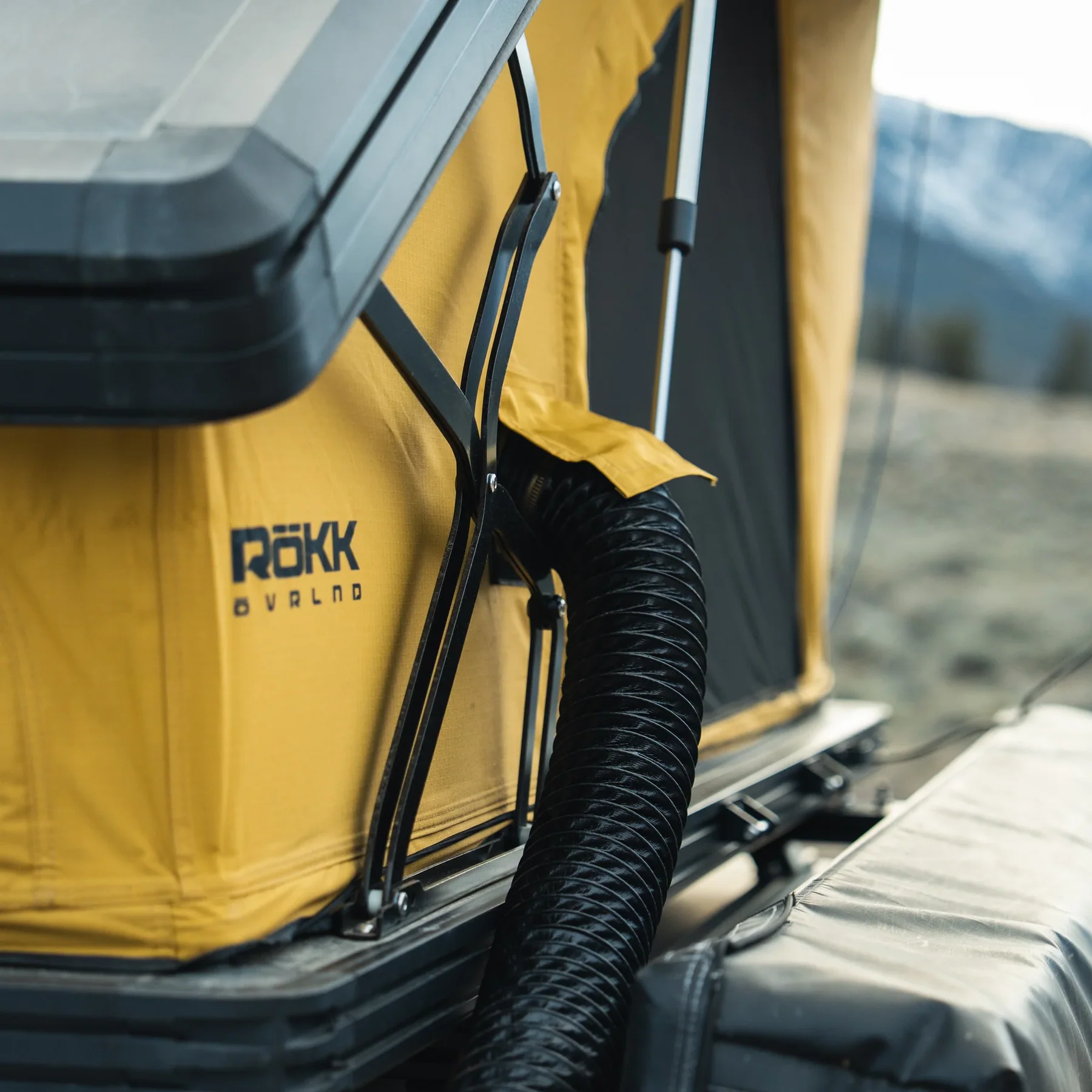 Close-up of the ROKK OVRLNDR 2P tent's diesel heater duct port feeding into the yellow tent wall