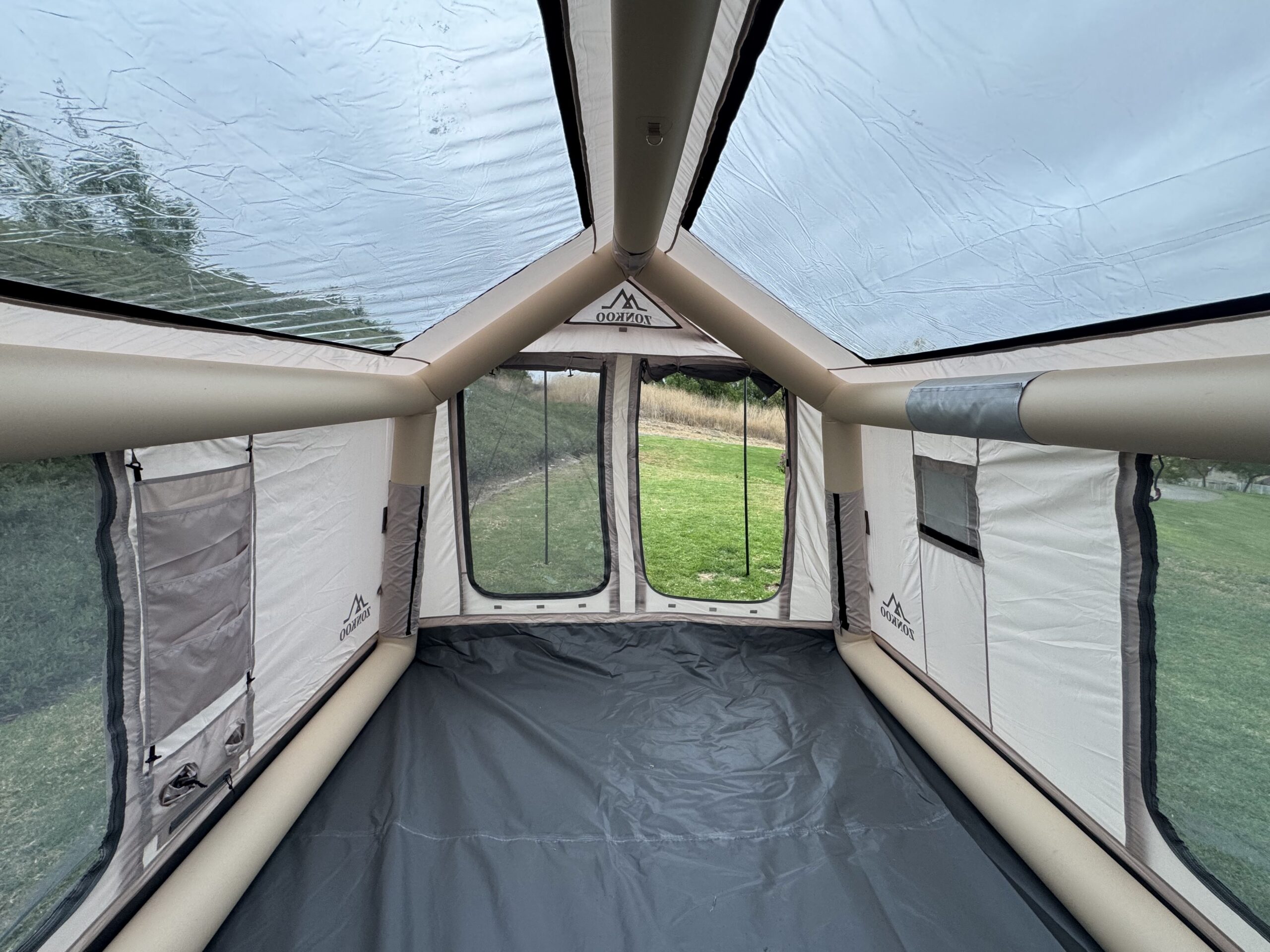 Looking toward the mesh double doors of the Zonkoo Orion inflatable tent from inside, with a grassy yard beyond
