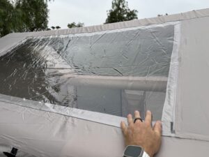 Hand pressing on the clear vinyl skylight panel of the Zonkoo Orion inflatable tent to show its texture
