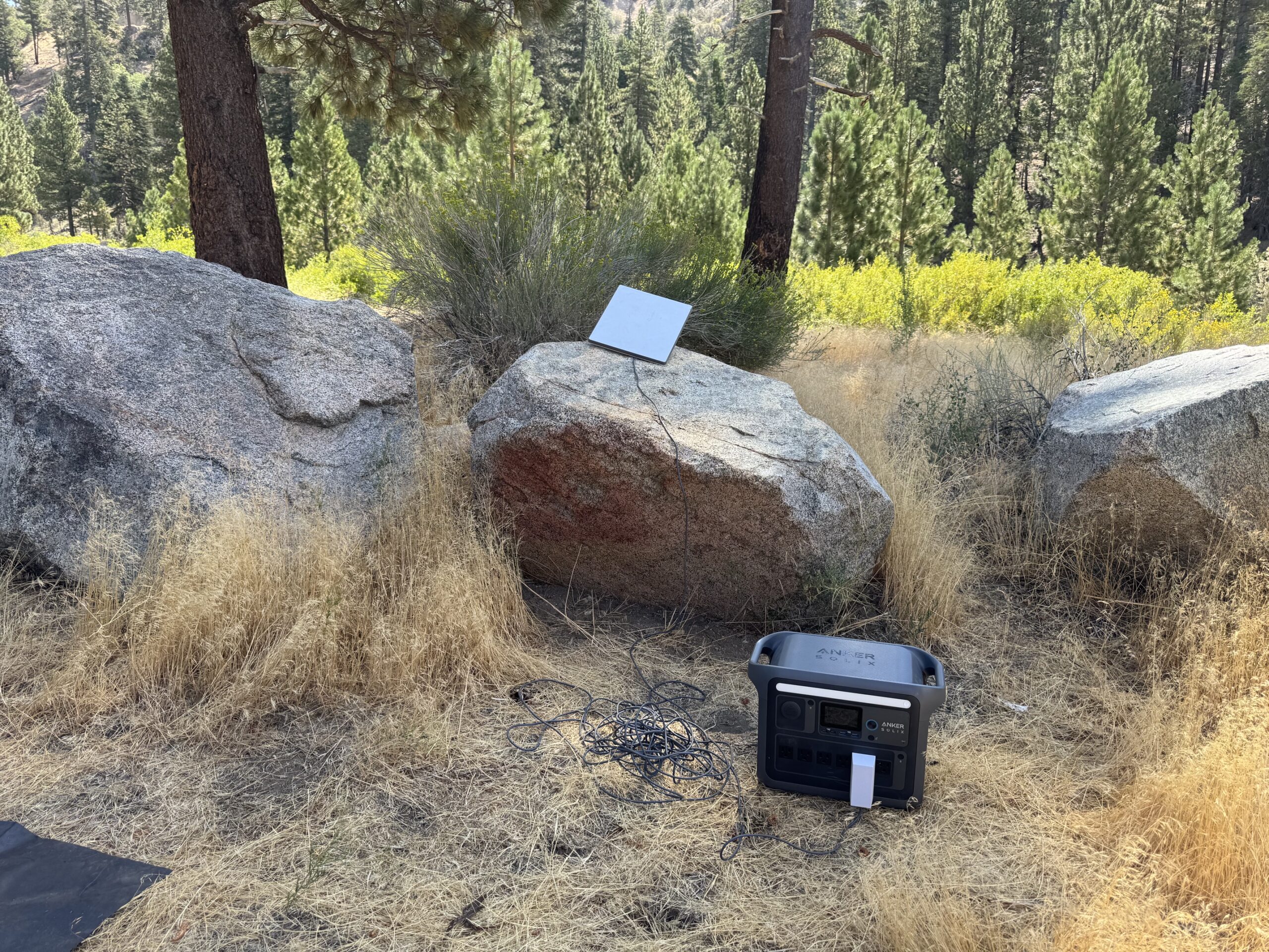 Starlink mini sitting on a rock plug into a portable battery.