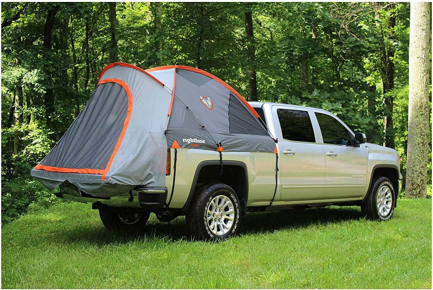 Rightline Gear truck bed tent in gray and orange pitched on a silver pickup parked in a grassy forest clearing
