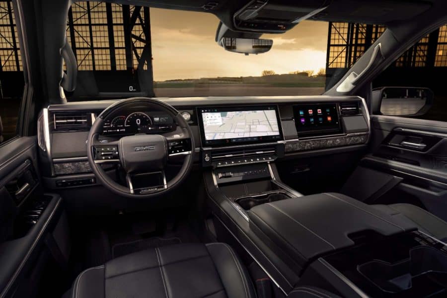 GMC Sierra Denali Ultimate dashboard with steering wheel, dual touchscreens, and head-up display active — manufacturer image