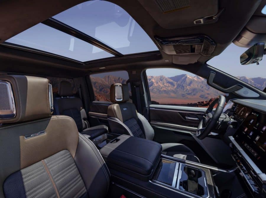 GMC Sierra AT4X interior with panoramic sunroof and desert mountain view through the open door — manufacturer image
