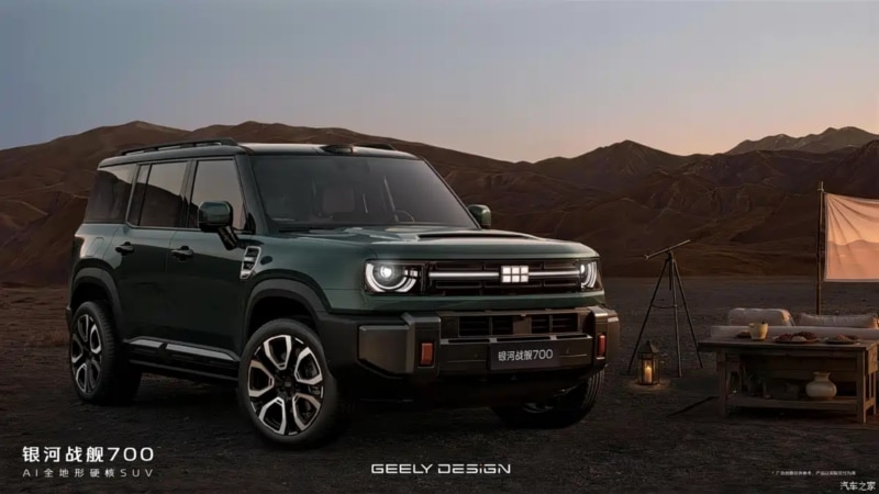 Dark green Geely Galaxy Cruiser 700 SUV parked in a desert campsite with a canvas tent and lanterns nearby — manufacturer image