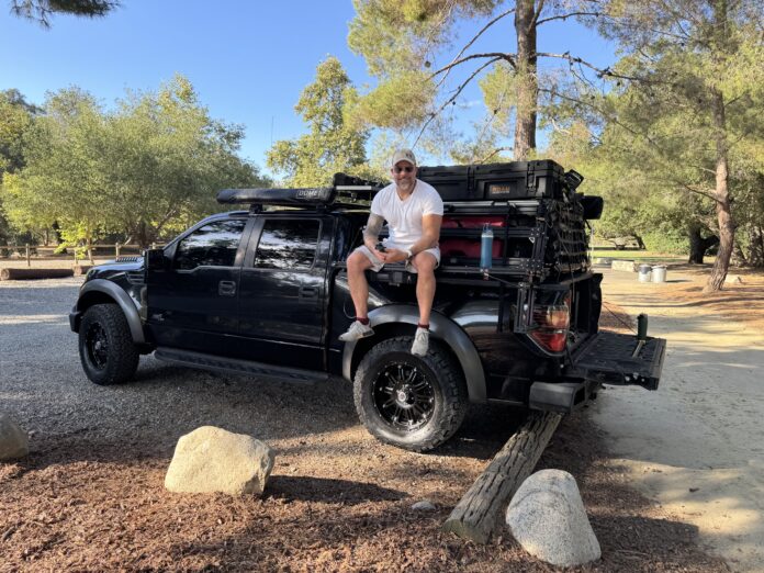 Alex sitting on the back of a 2013 Ford Raptor with a Yassa step installed
