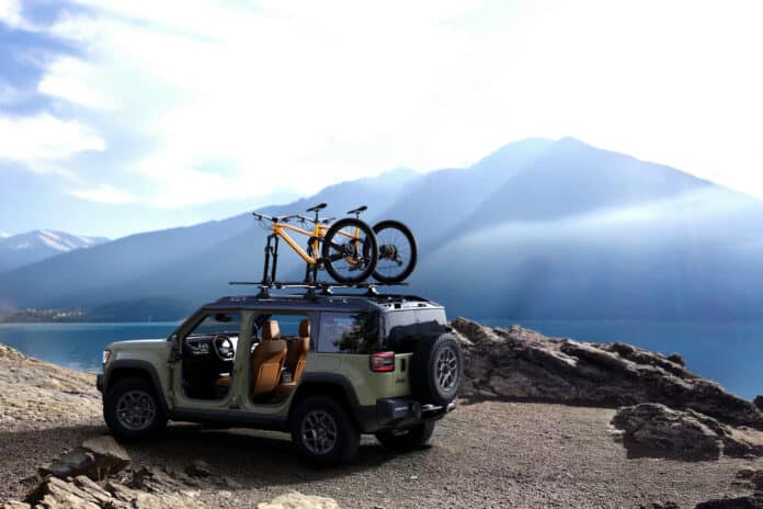 Green 2026 Jeep Recon with doors removed and two mountain bikes on the roof, parked above a mountain lake