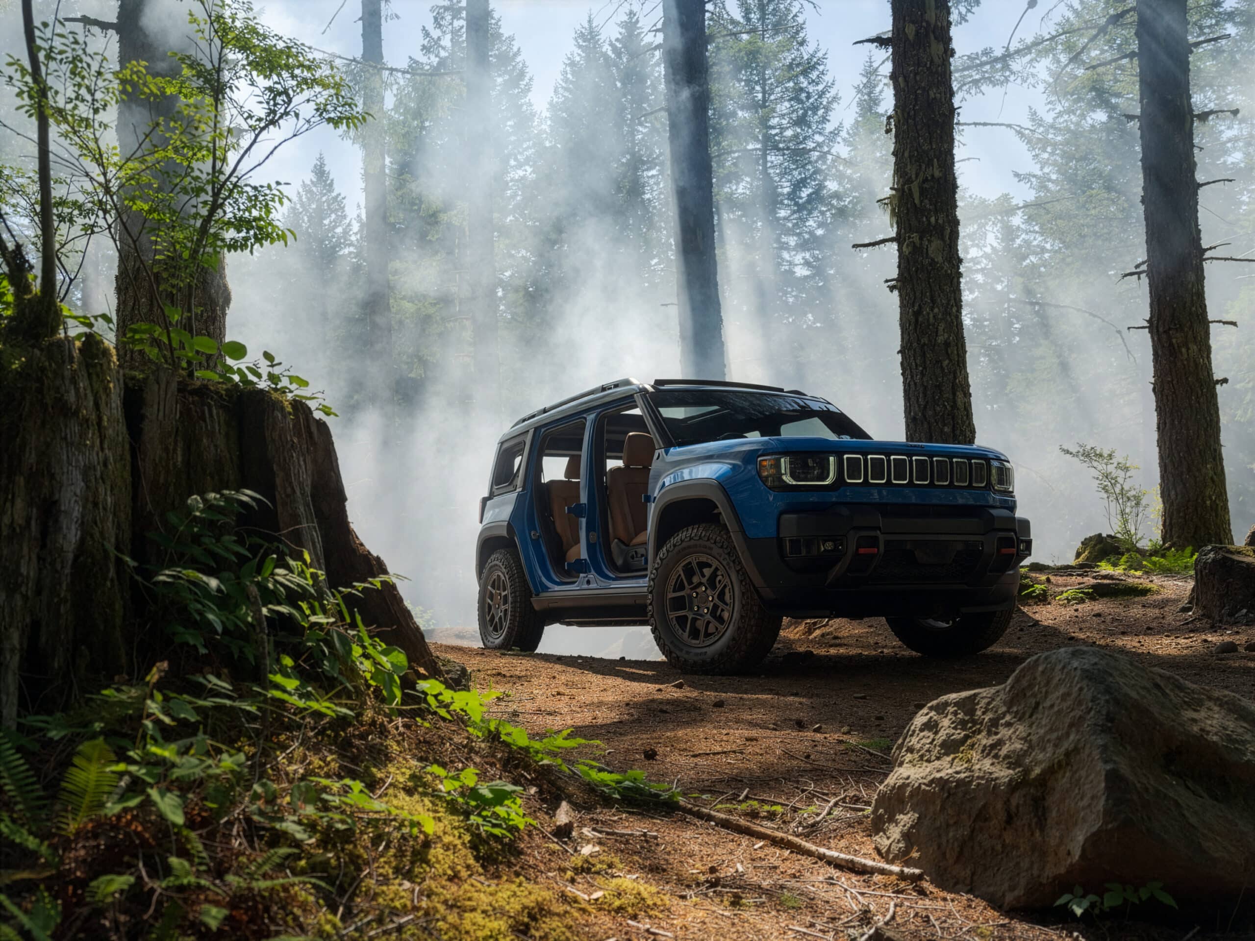 Blue electric Recon with its doors off on a misty forest trail