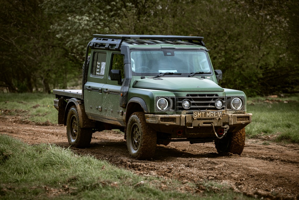 Ineos Grenadier MRLV front three-quarter view on a muddy trail with round LED headlights