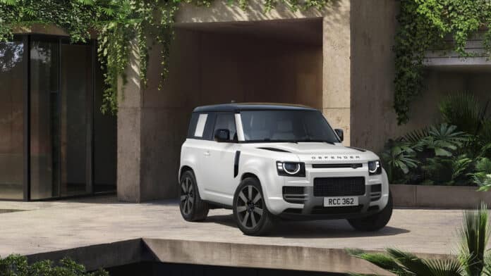 2027 Land Rover Defender Vertex in white with a black roof, 22-inch wheels, and yellow brake calipers parked outside a modern villa