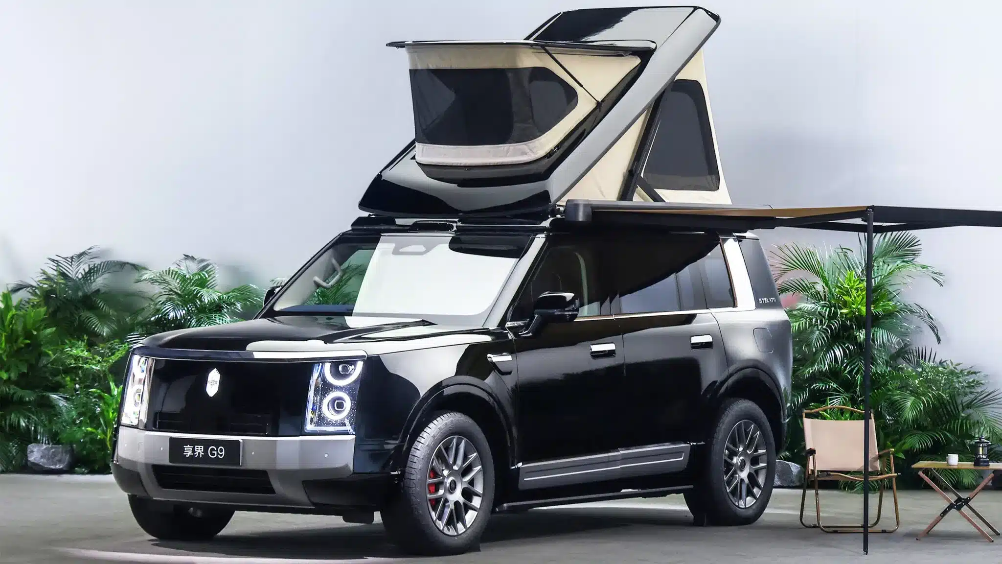 Body-integrated electric roof tent and side awning open on a black luxury SUV at a launch display