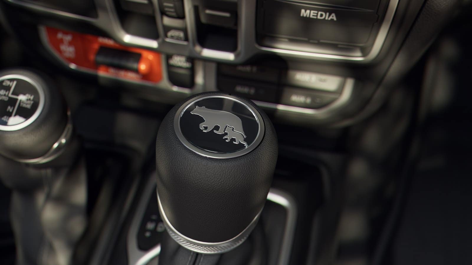 Shifter medallion in a 2027 Jeep Wrangler Smoky Mountain showing a mama bear and cub graphic, with the transfer case lever alongside