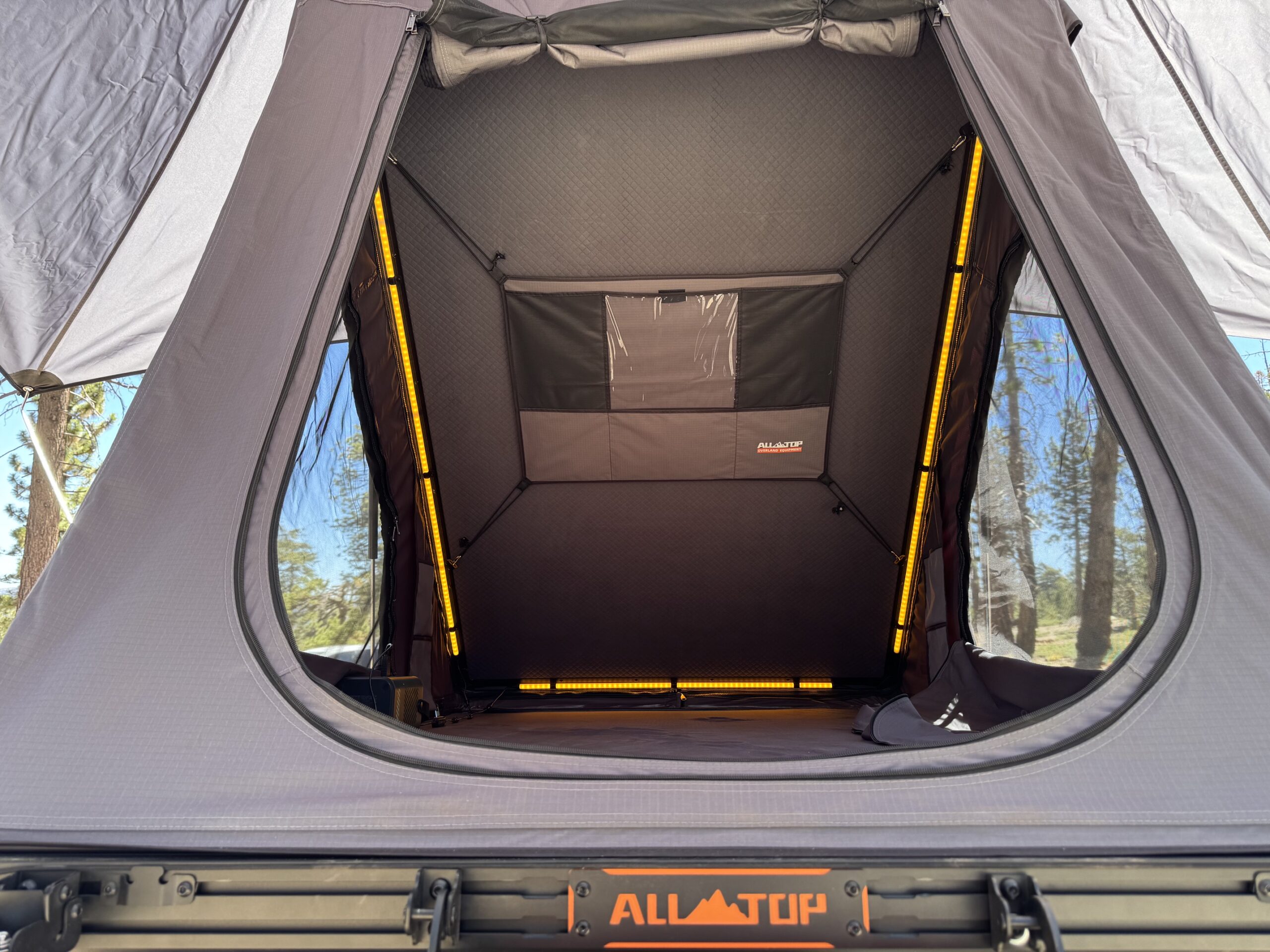 Interior of the ALL-TOP Apexcamp hard shell wedge tent with amber LED strips lit and the storage panel on the end wall