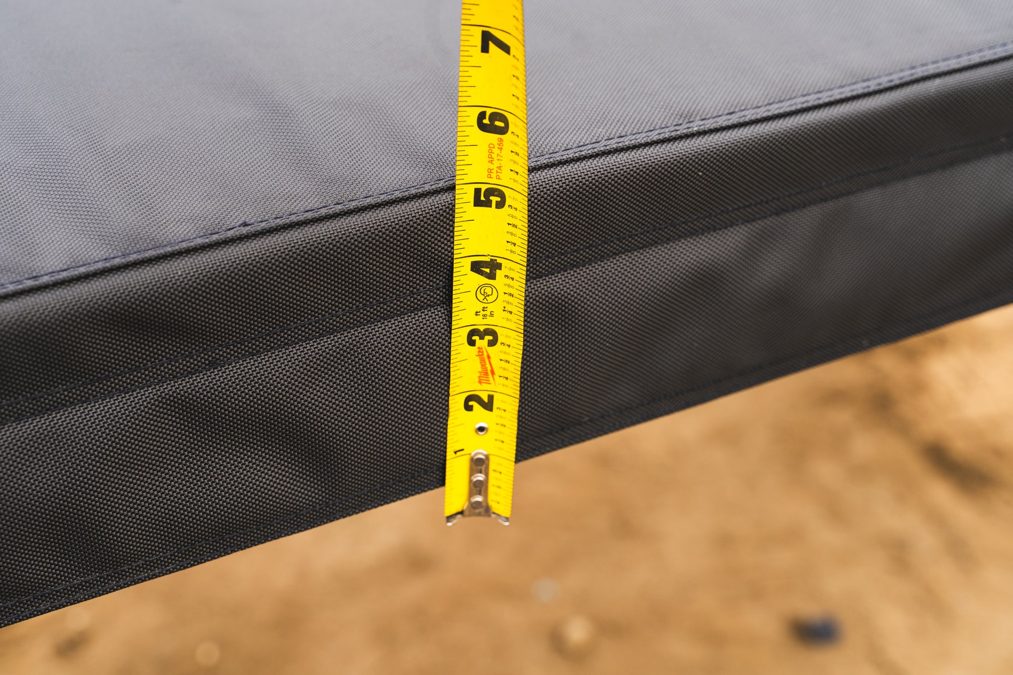 Tape measure held against the closed Featherlyte Baseline shell showing roughly a 7 inch packed height