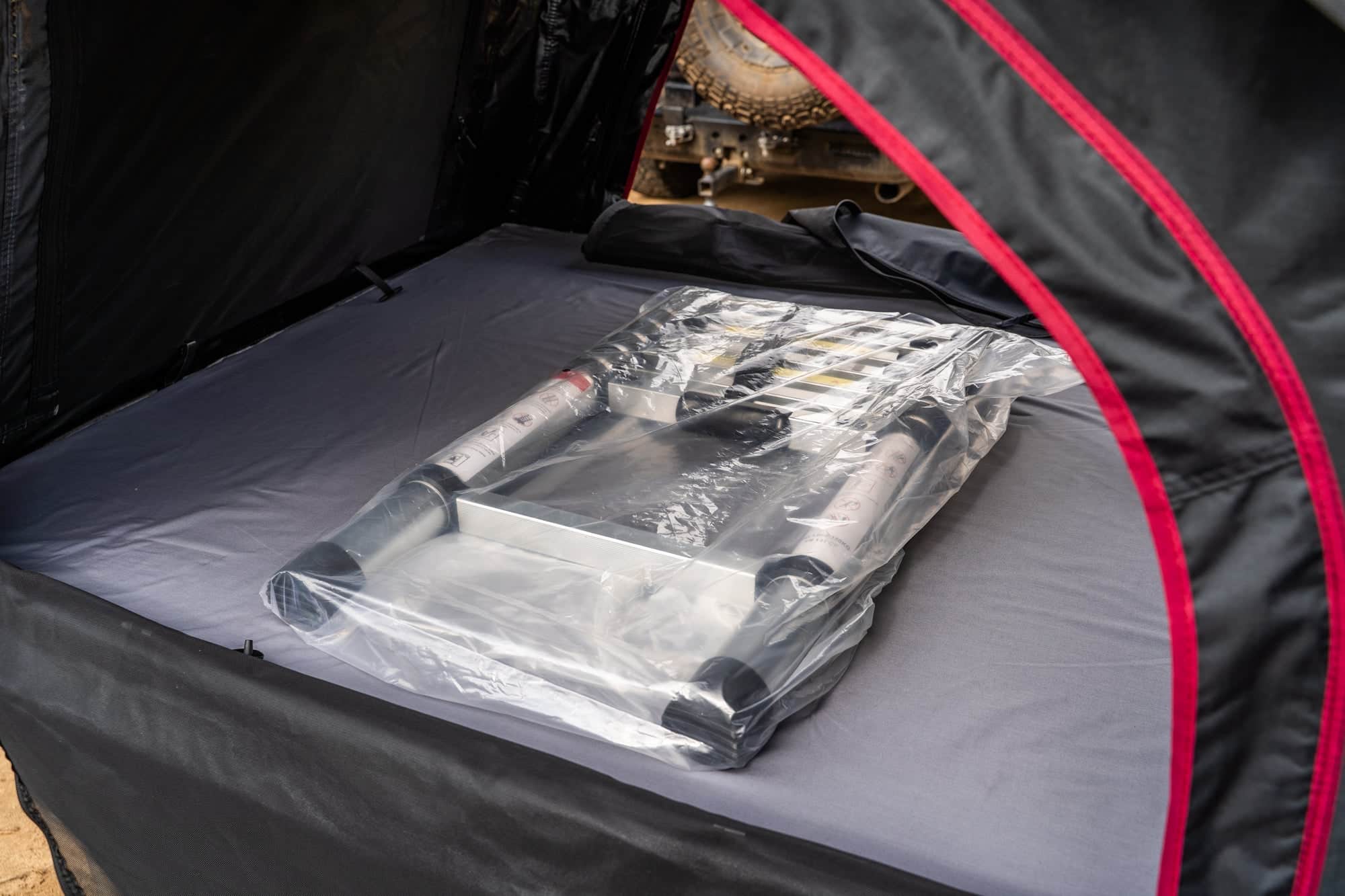 Interior of the Featherlyte Baseline rooftop tent showing the grey mattress and red piped door zipper