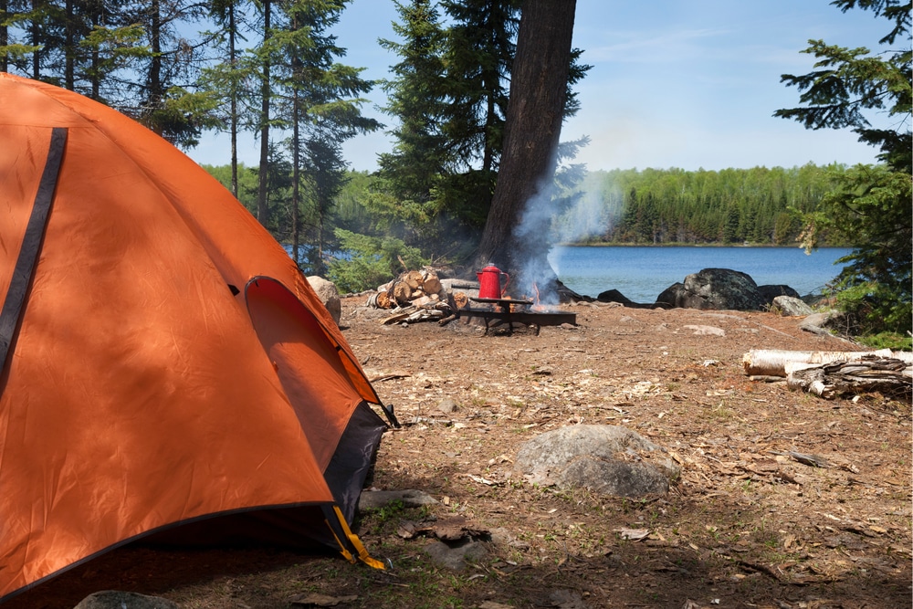 Orange tent and a campfire coffee pot at a first come first served lakeside site, one door into sold out campgrounds
