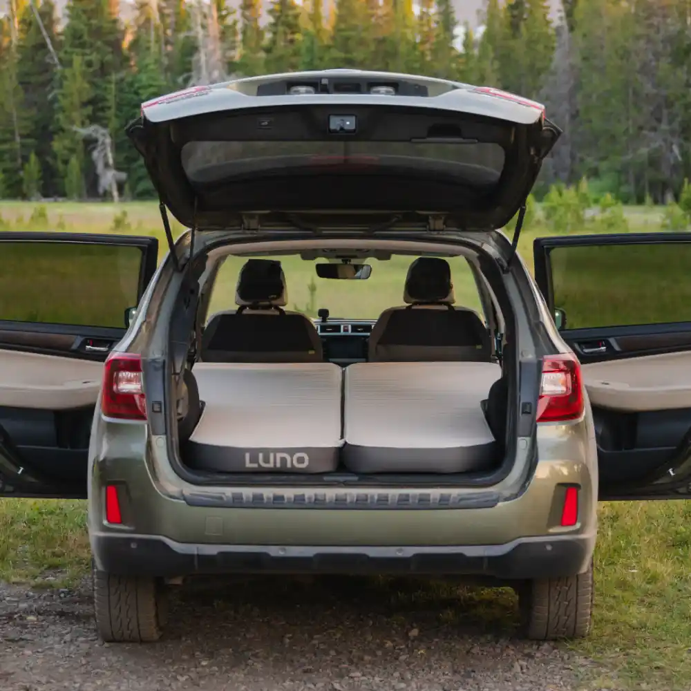 Luno AIR+FOAM PRO vehicle mattress installed in a Subaru Outback cargo area at a forest campsite