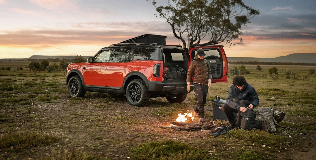 Ford Bronco Basecamp prototype with the pop-up roof raised and swing gate open at a campsite
