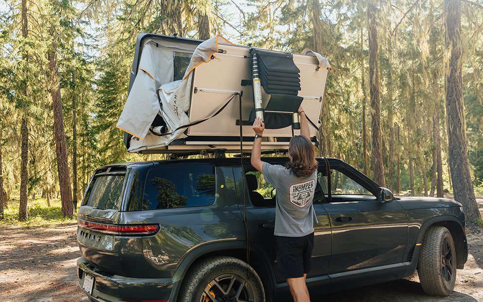 Person unfolding the Skycamp 4.0 DLX with its HC Staircase ladder on the roof of a Rivian R1S