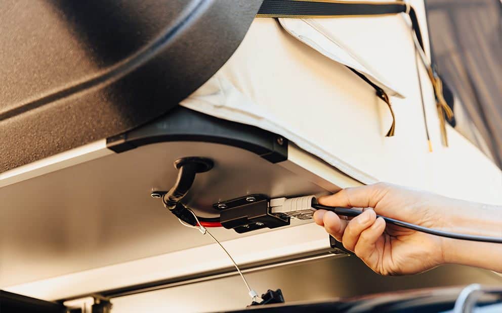 Hand connecting a power cable to the port under the Skycamp 4.0 DLX base