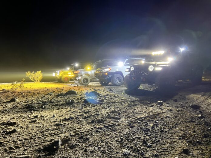 Toyota's and Jeeps lined up off-road with lights on in Anza Borrega
