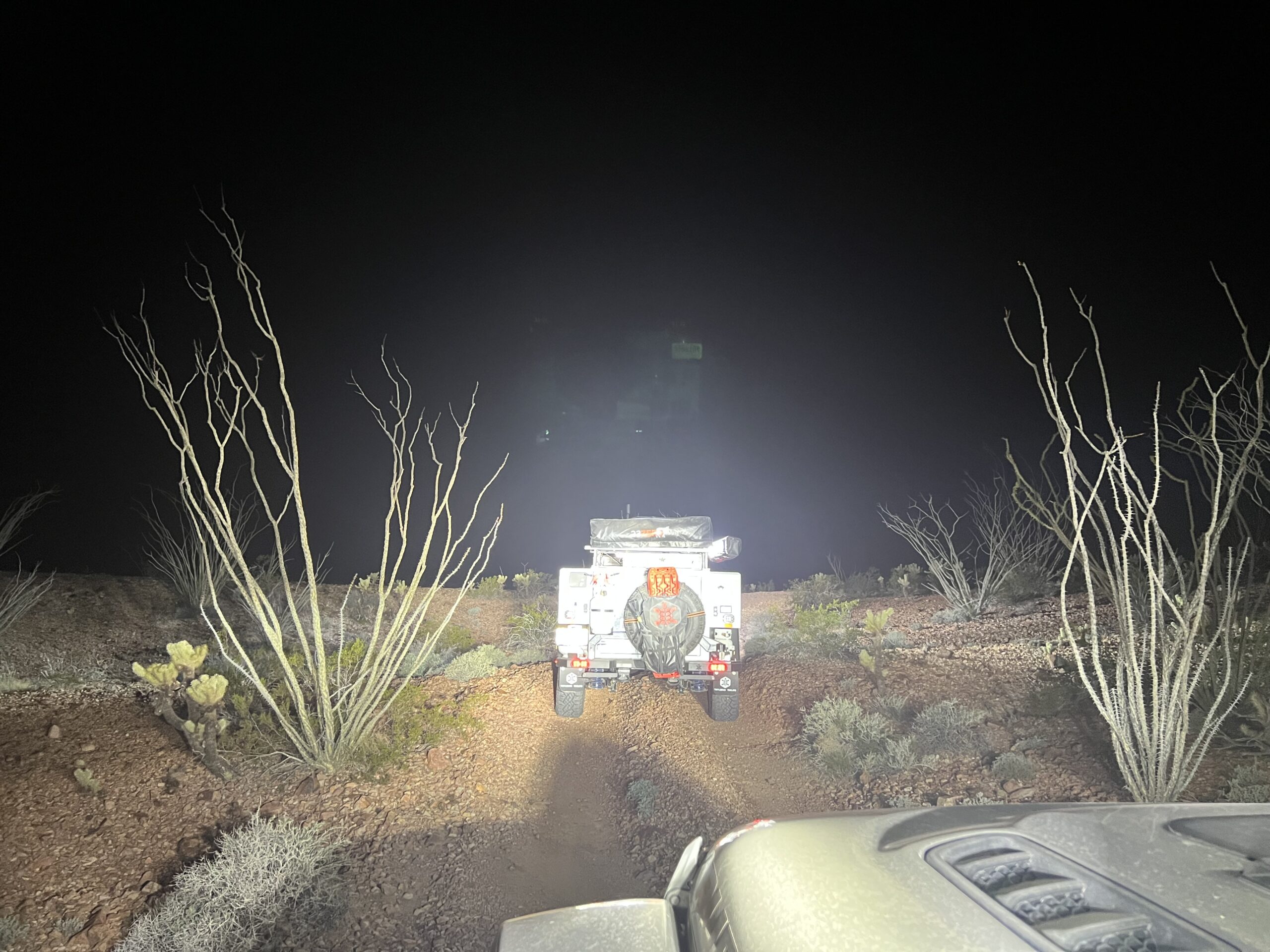 A gladiator behind a Toyota 4Runner in the desert at night