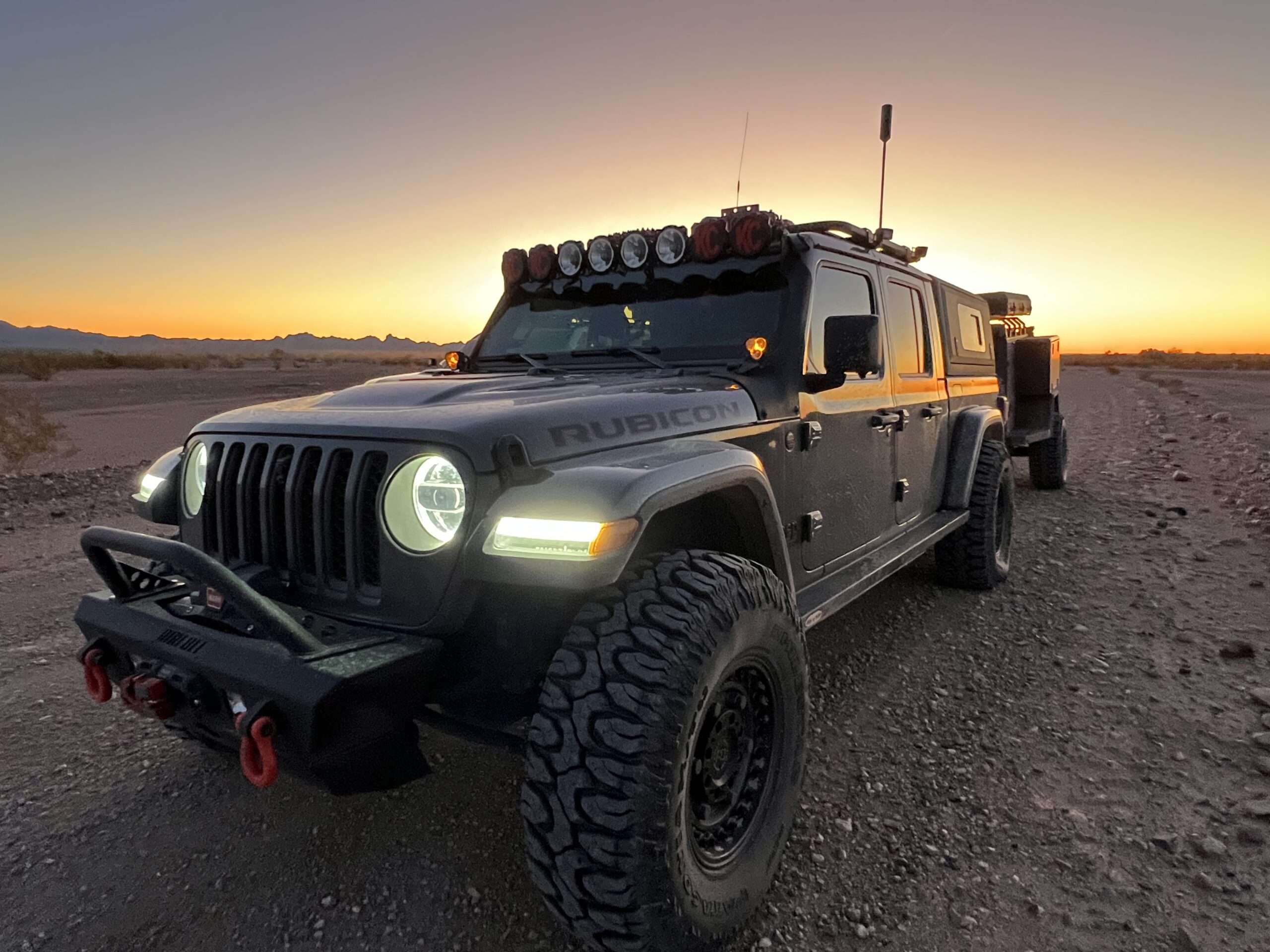 Jeep Gladiator with lights on during a sunrise