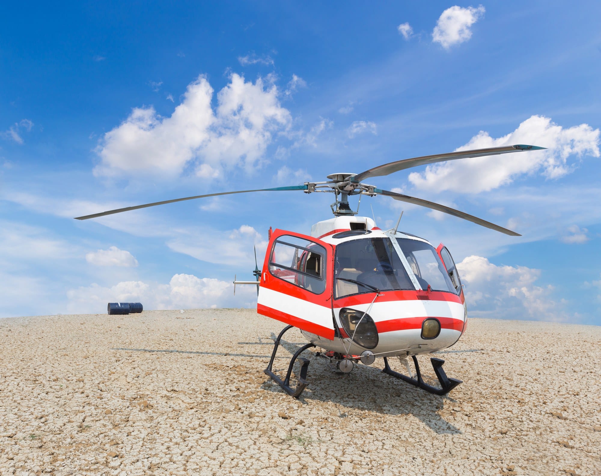 Rescue helicopter on a dirt landing zone Red and white rescue helicopter parked on a cracked dirt landing zone