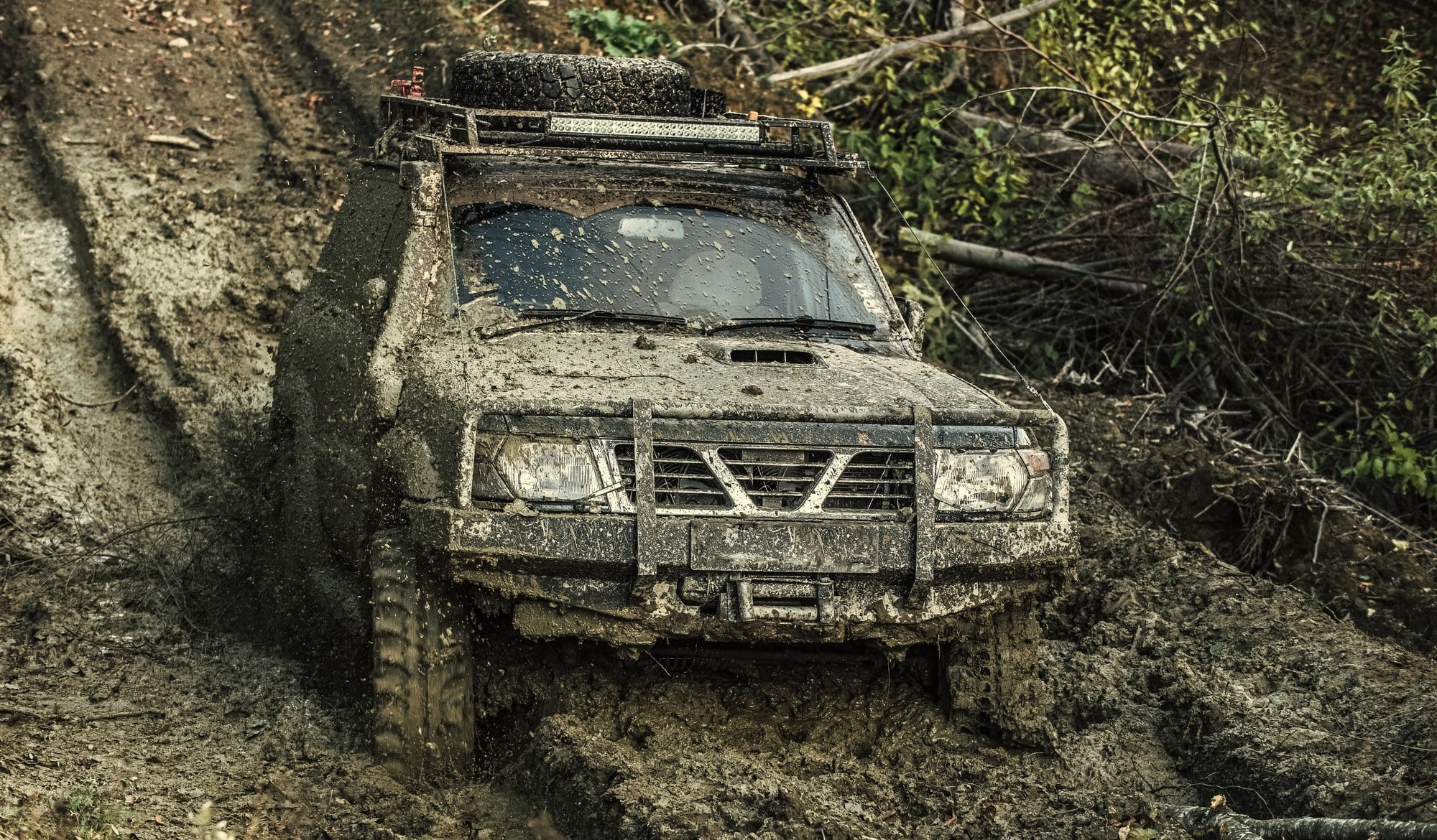 Off-road vehicle stuck on a muddy trail Mud-covered off-road SUV stuck on a forest trail
