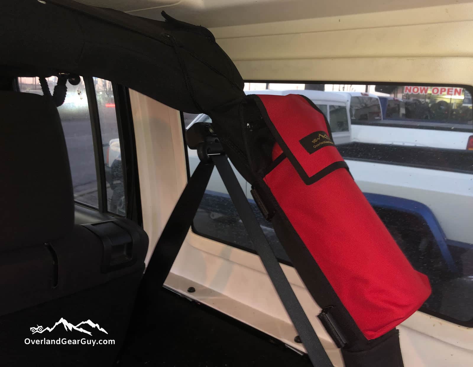 Red fire extinguisher pouch strapped to a padded roll bar behind the front seat