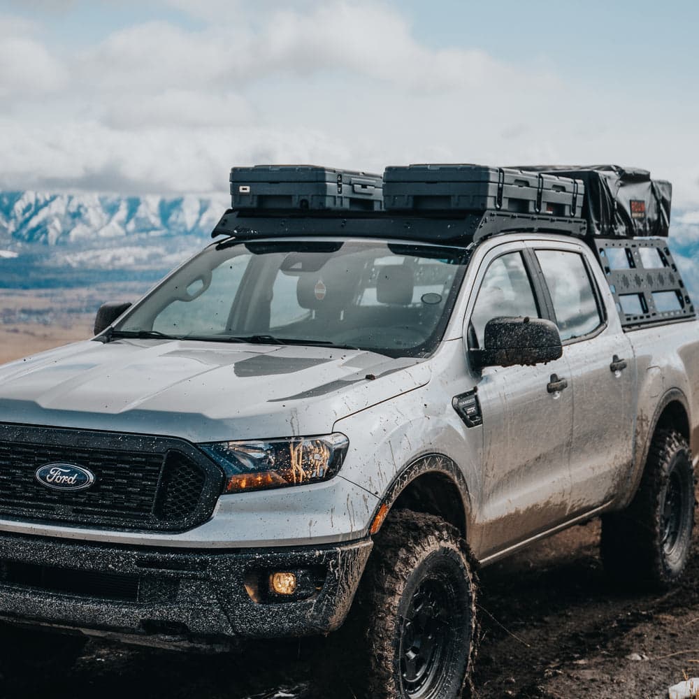 Roam 83L Rugged Cases on a roof rack Two Roam Adventure Co. Rugged Cases mounted on the roof rack of a muddy Ford Ranger