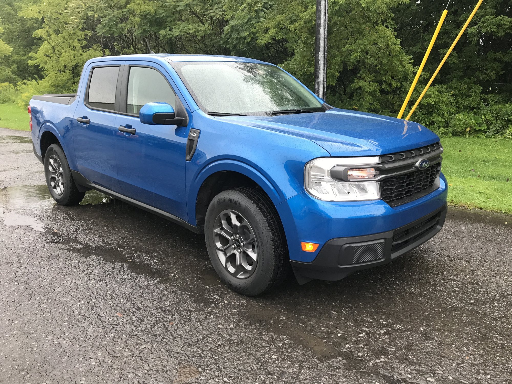 Stock Ford Maverick XLT Before the Tucci Hot Rods Build Stock blue Ford Maverick XLT with factory gray alloy wheels parked on wet pavement before the Tucci Hot Rods build