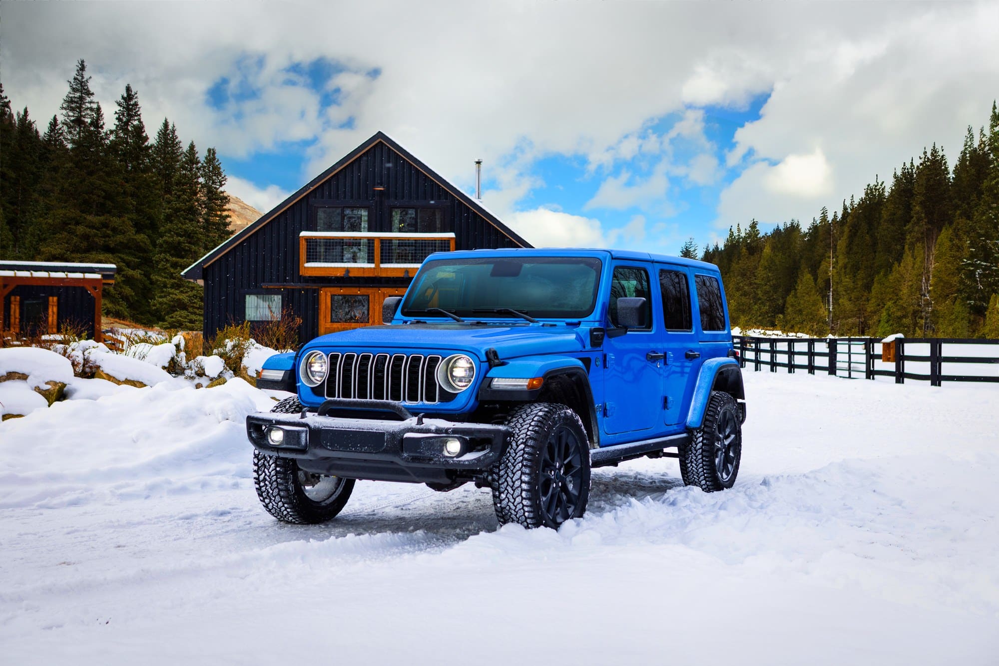 Jeep Wrangler press photo Blue 2025 Jeep Wrangler 4xe parked in snow outside a cabin