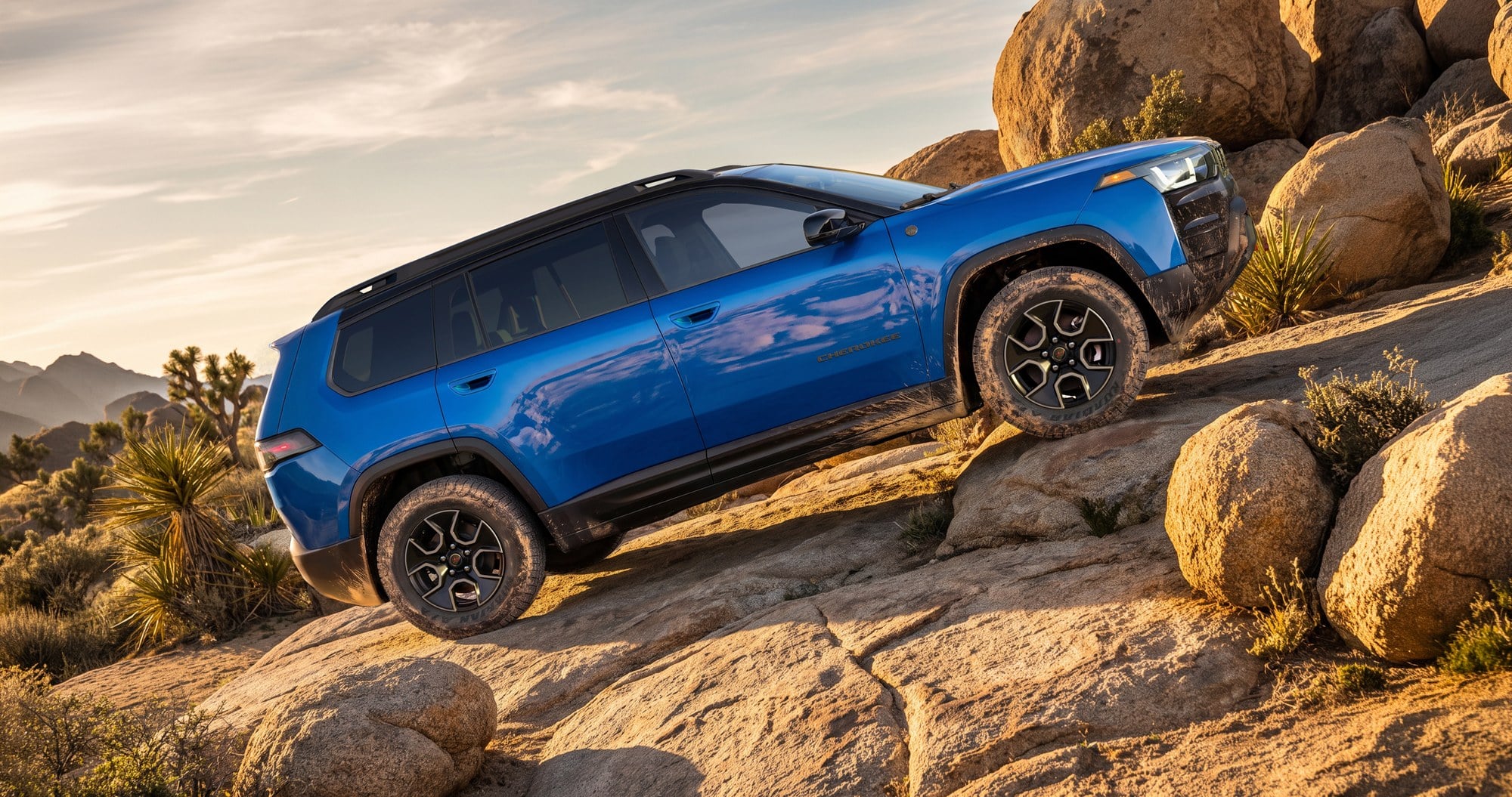 Blue Jeep SUV in side profile climbing a rocky hill, showing its raised off-road stance