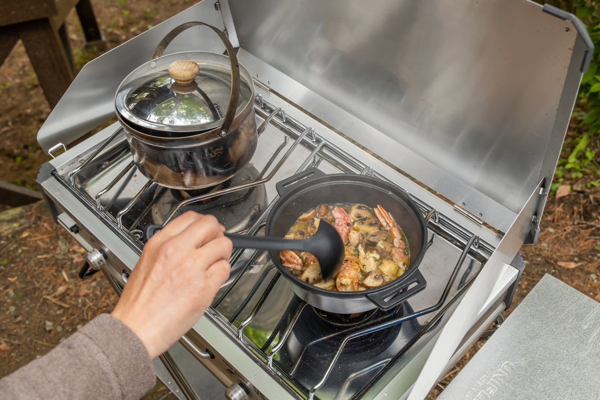 Two-burner camp stove Cooking with a kettle and a pan on a two-burner camp stove at a campsite