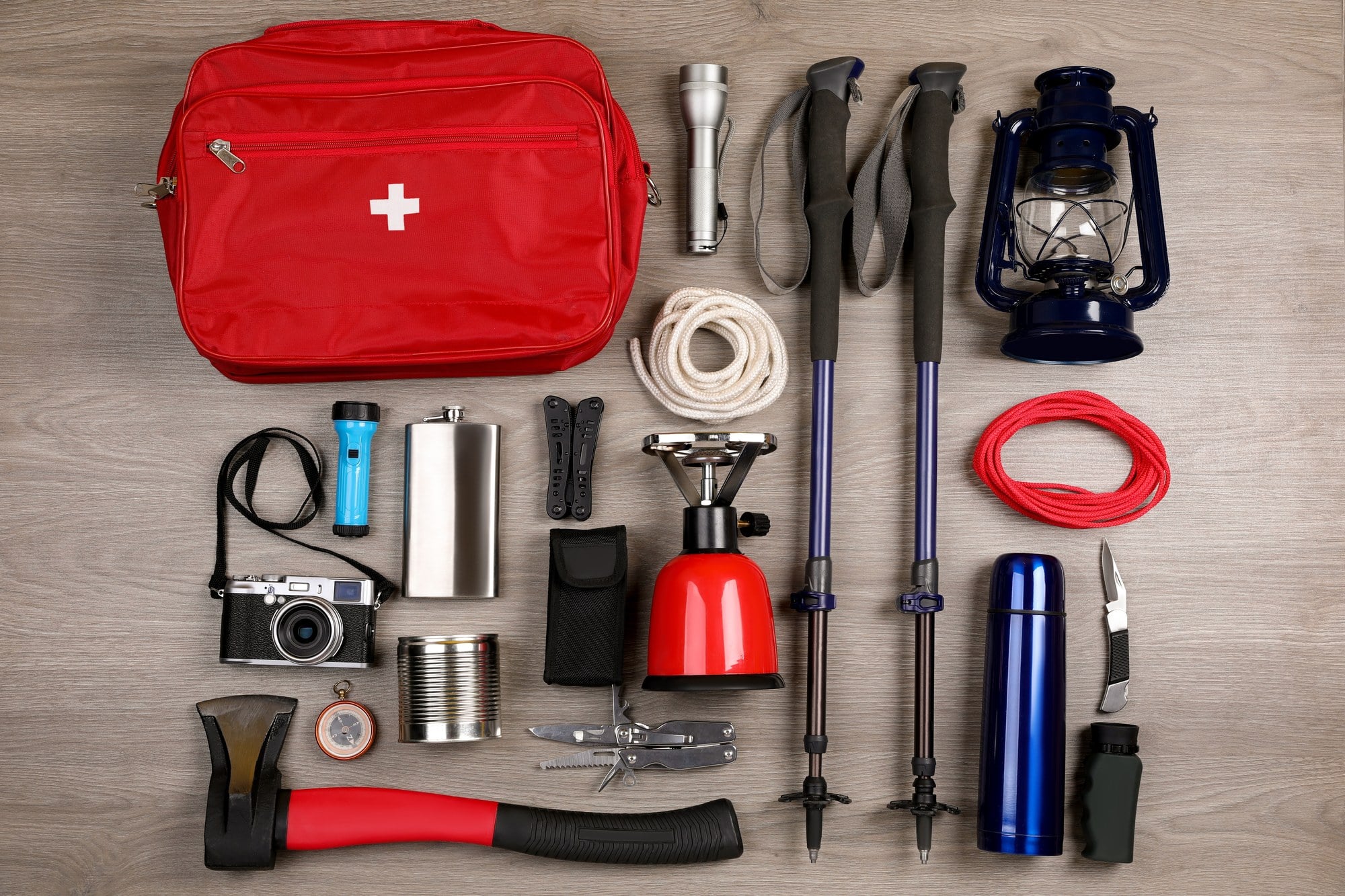 Camp kit laid out First aid kit, flashlight, lantern, camp stove and trekking poles laid out on a wooden floor