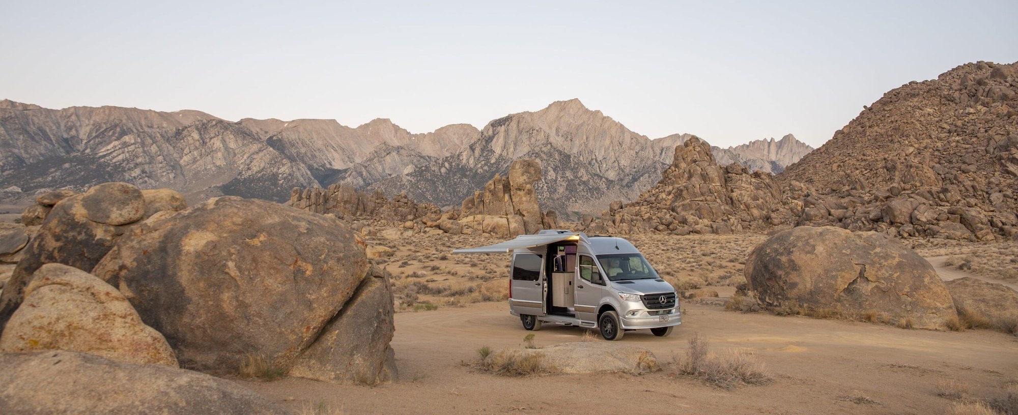Grech Turismo motorhome Grech Turismo Sprinter motorhome parked among desert boulders below a mountain range