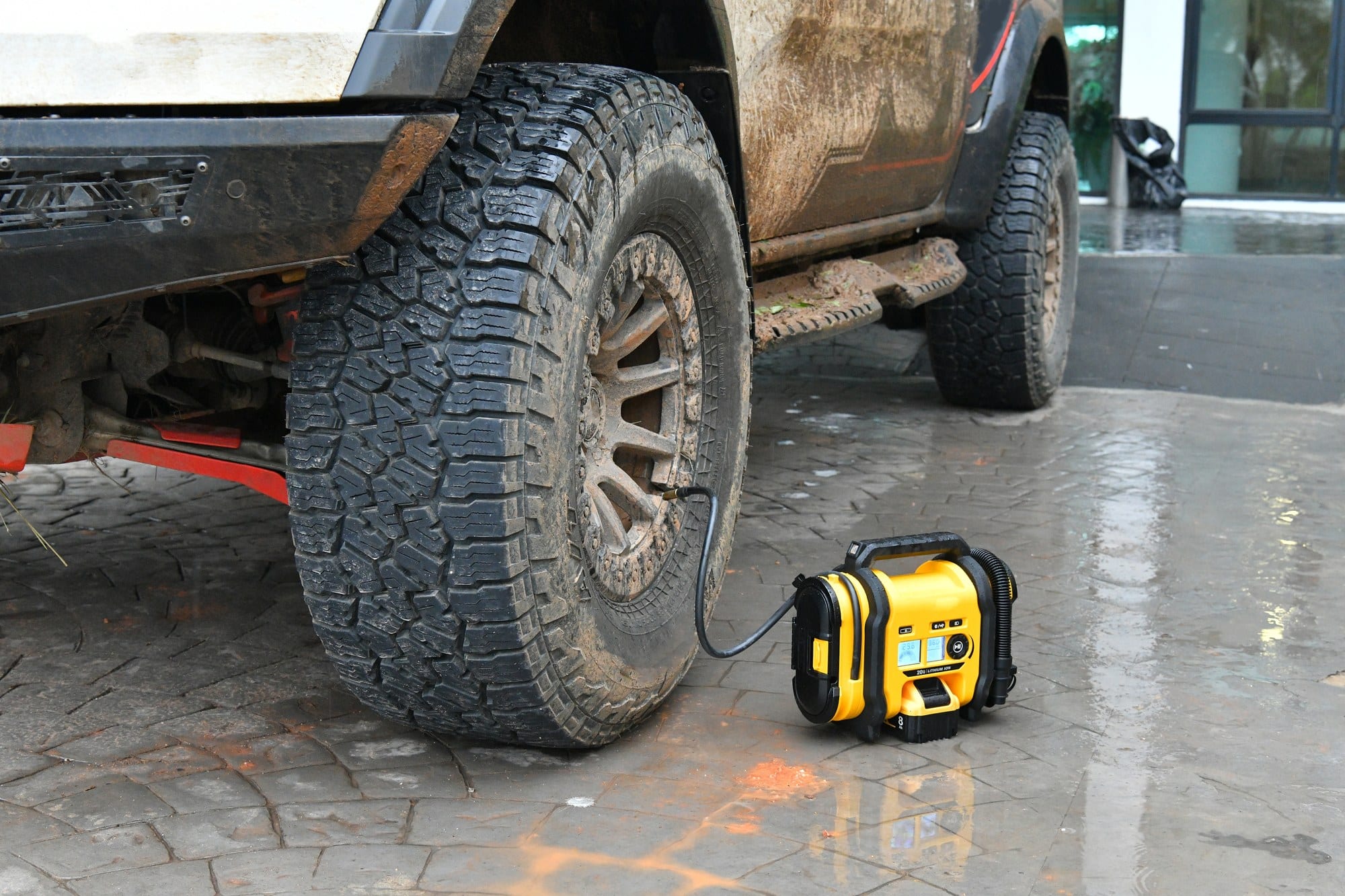 Airing up after a trail run Portable air compressor inflating a muddy all-terrain tire on an off-road truck