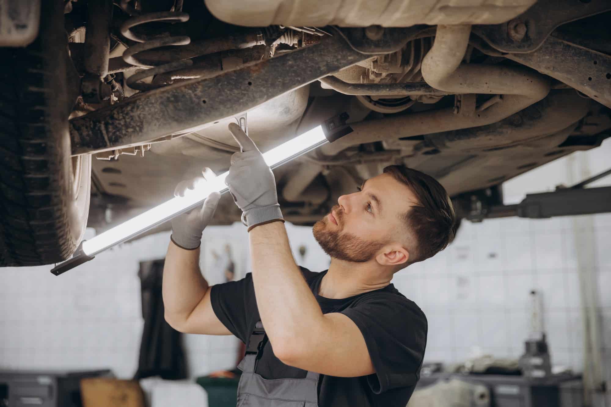 Undercarriage inspection with a work light Mechanic using a work light to inspect the running gear under a raised vehicle