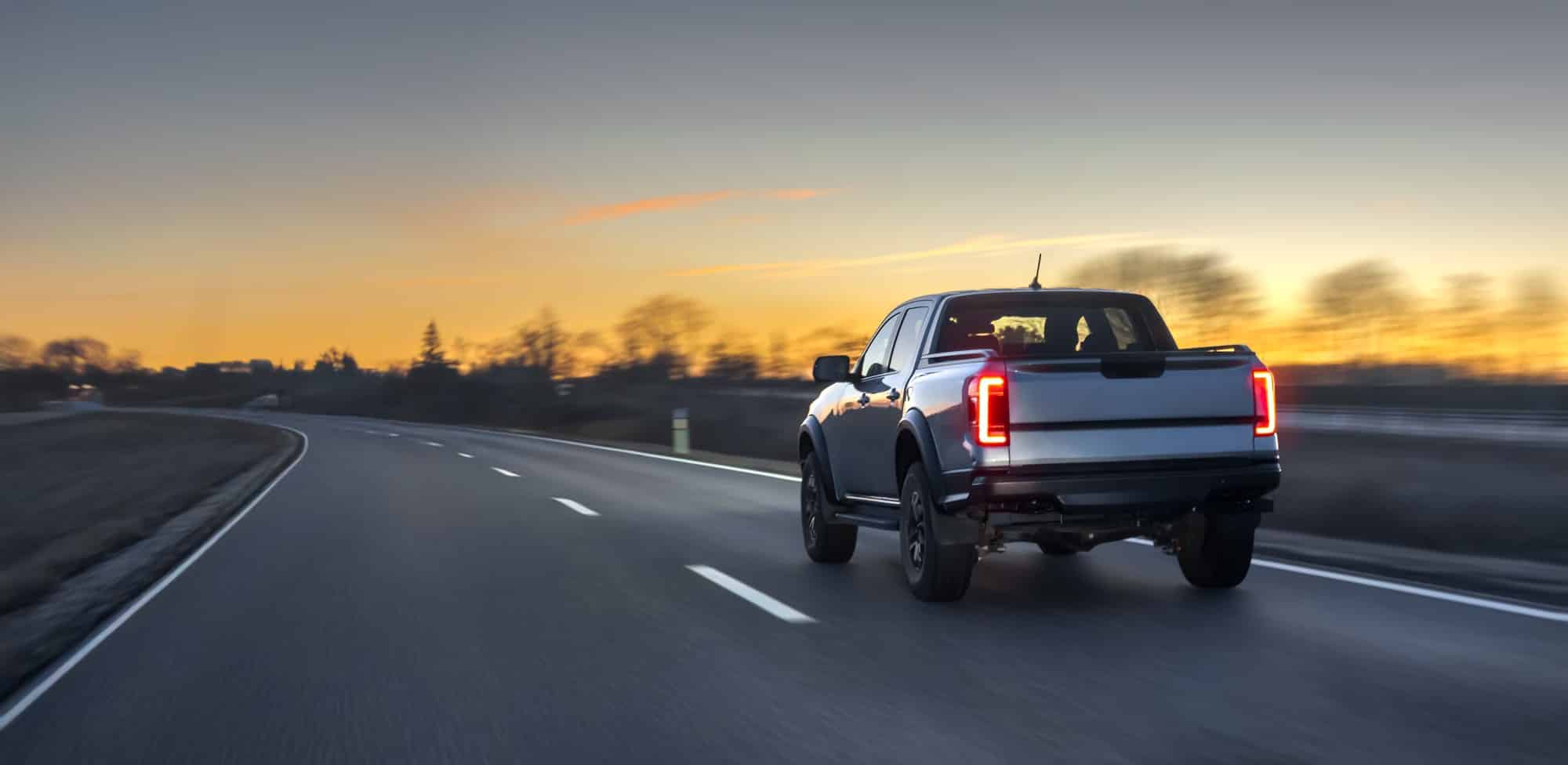 Pickup truck driving on a highway at sunset